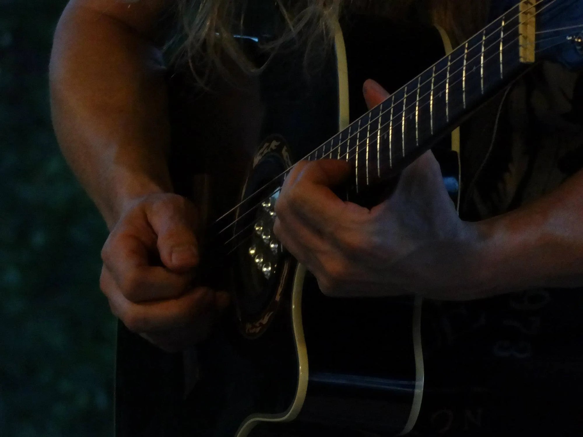 Close up angled shot of a black guitar being played