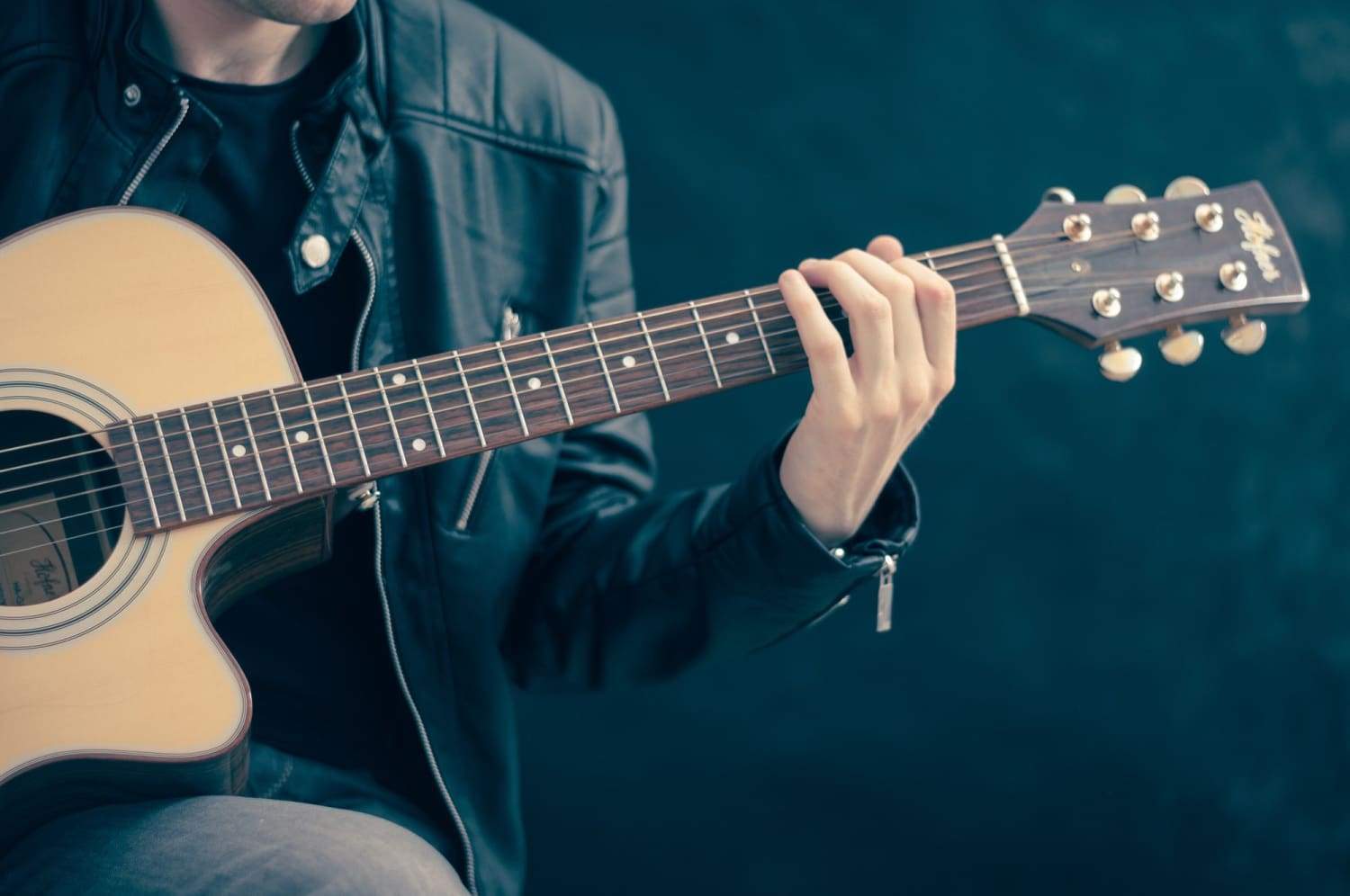 man wearing jacket playing guitar