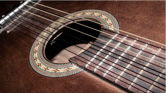 A close up view of a brown guitar sound hole area