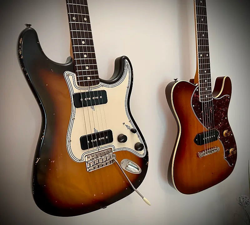 2 Tophat guitars hanging on wall