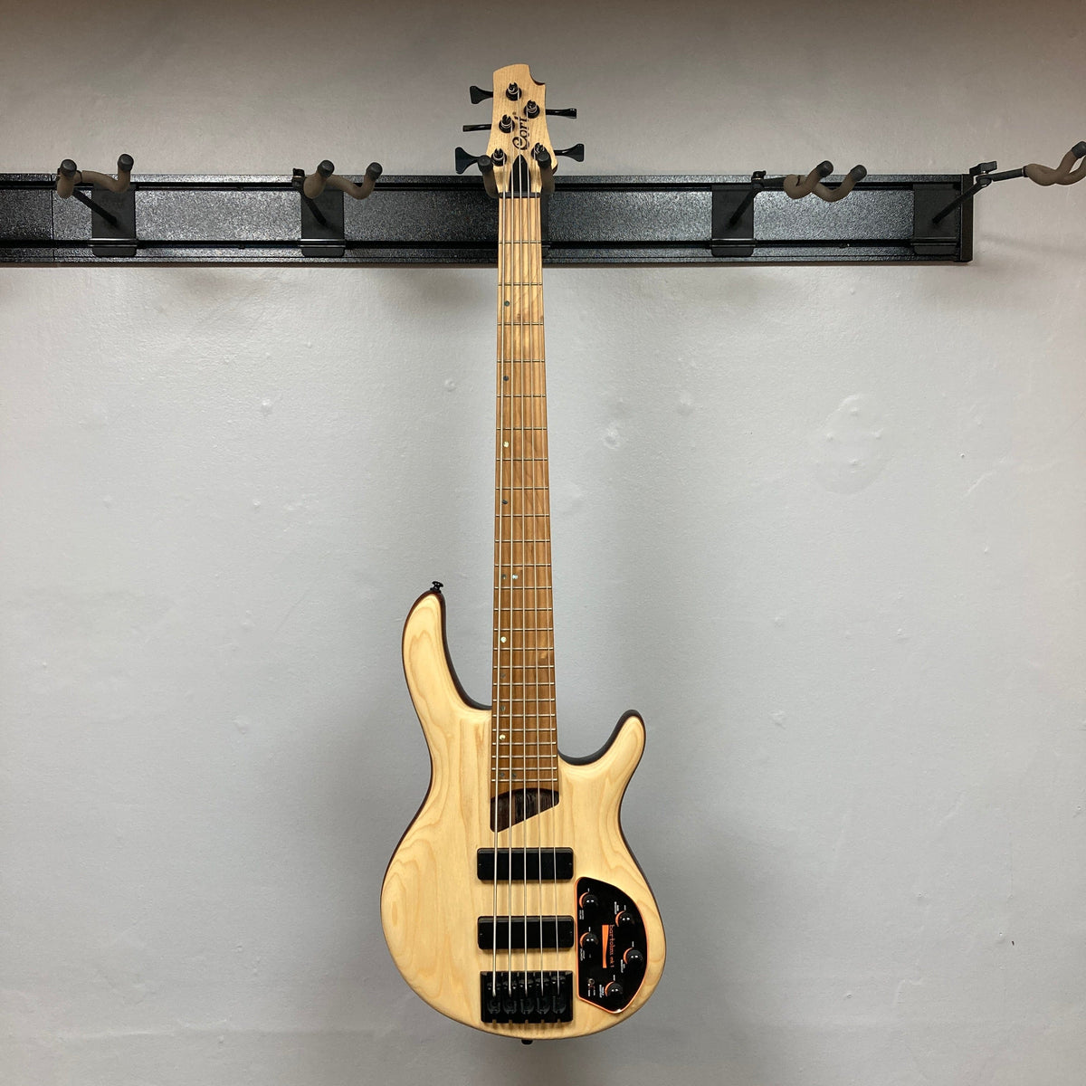 Cort Artisan B5 Element Natural Used guitar displayed on a wall, highlighting its intricate string setup and craftsmanship, perfect for music enthusiasts.