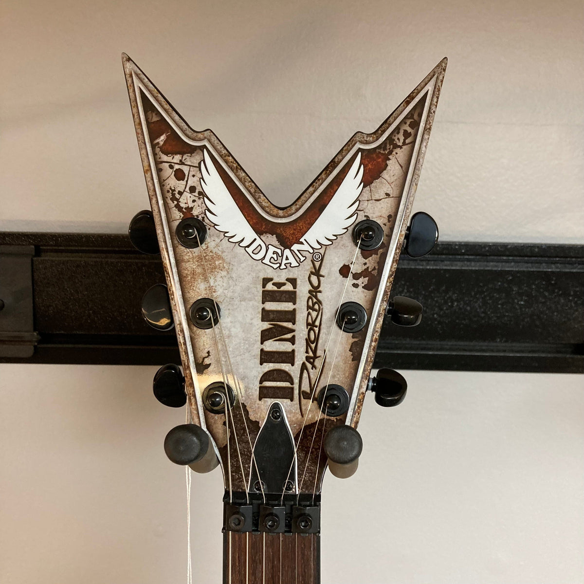 Dean Razorback Rust electric guitar close-up featuring headstock logo and minor blemishes, ideal for hard rock and metal tones, with included protective case.