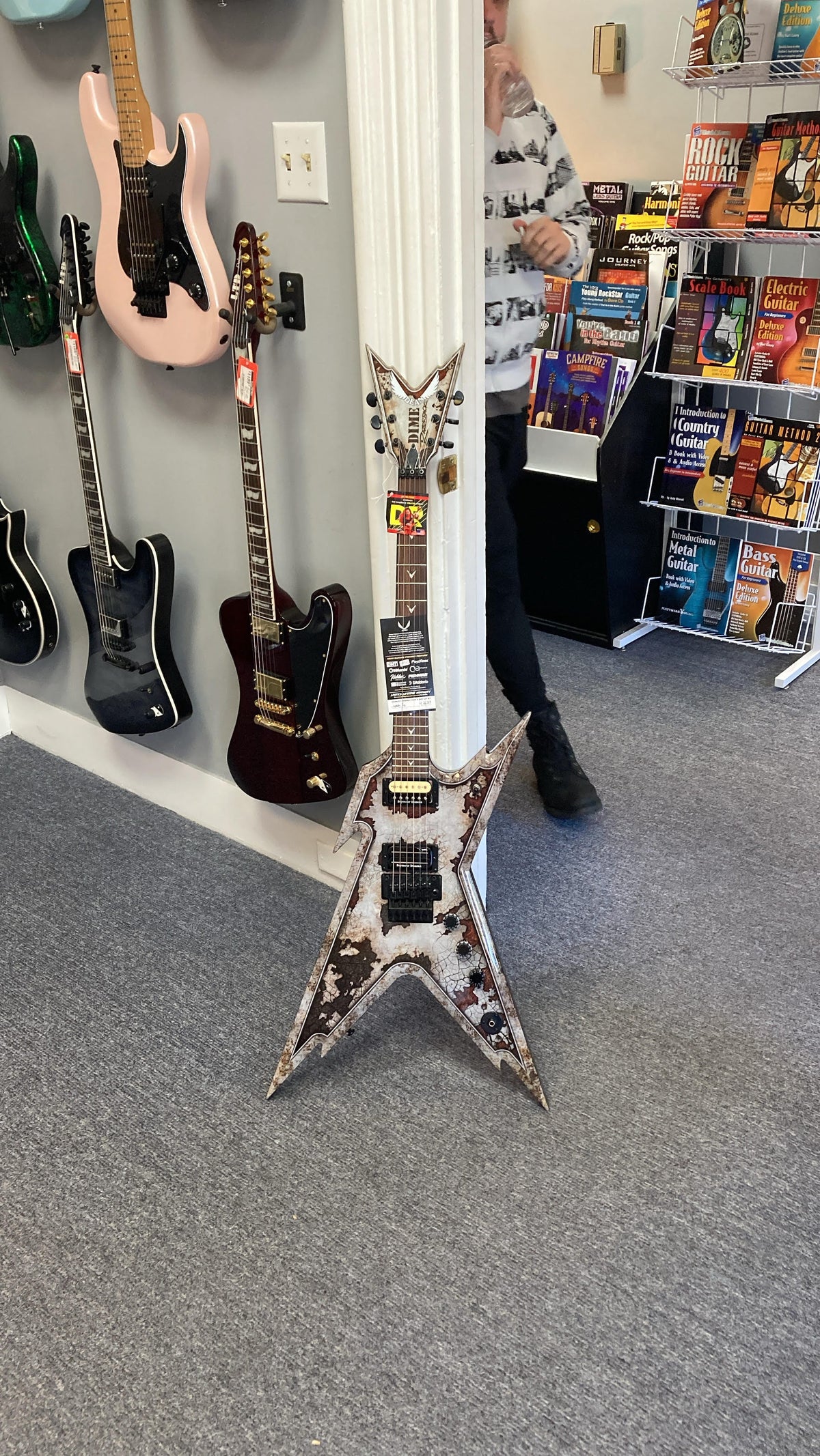 Dean Razorback Rust electric guitar with custom rust graphic, leaning against a wall, showcasing its professional-grade features and design. Includes case.