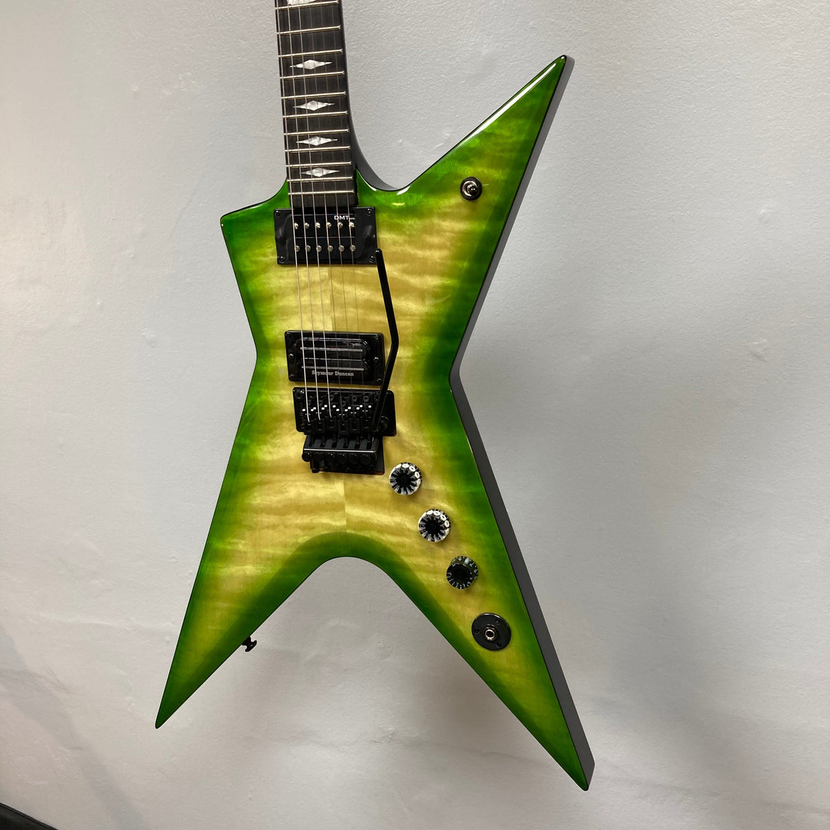 Dean Stealth Floyd FM Dime Slime electric guitar mounted on a wall, highlighting its sleek design and high-performance features.