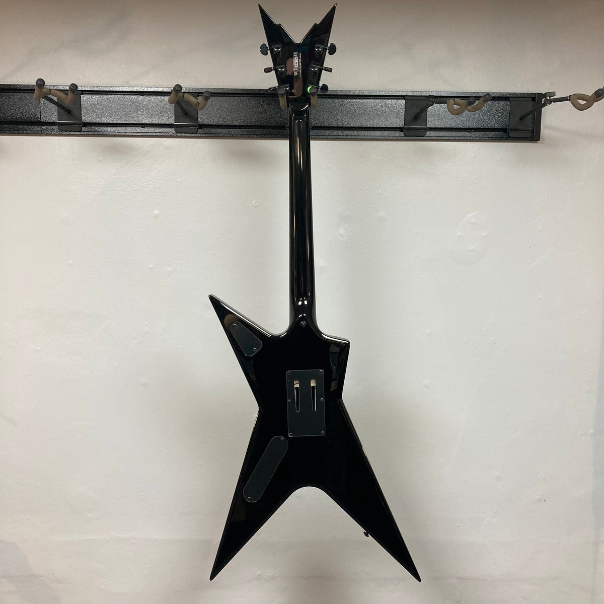 Dean Stealth Floyd FM Dime Slime guitar on a wall hook, showcasing its sleek design and black hardware.