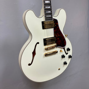 Epiphone IGC 1959 ES-355 Classic White Electric Guitar with gold hardware, displayed on a wall, highlighting its vintage design and intricate detailing.