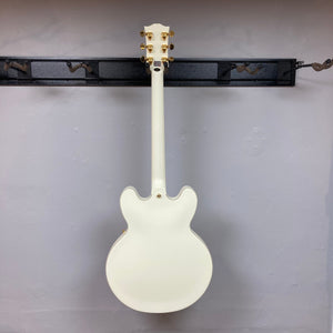 Epiphone IGC 1959 ES-355 Classic White Electric Guitar with gold hardware and mother-of-pearl inlays displayed on a wall.