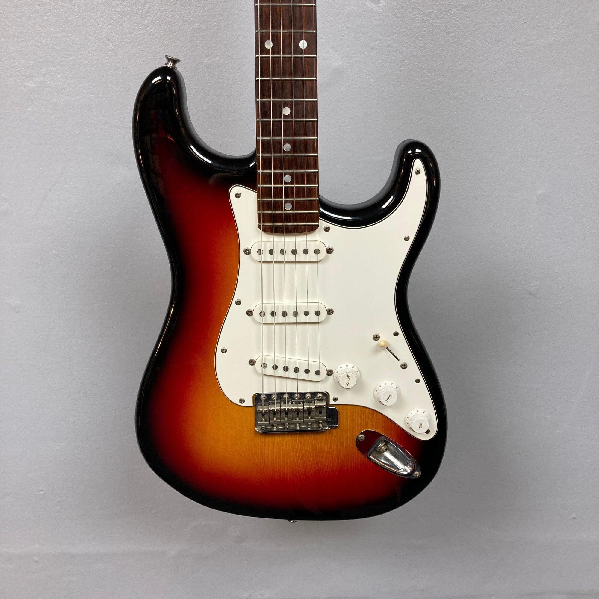 ESP Japan 400 Series Strat style guitar displayed on a wall, showcasing strings and a white knob, includes a case for sale at Guitars on Main.