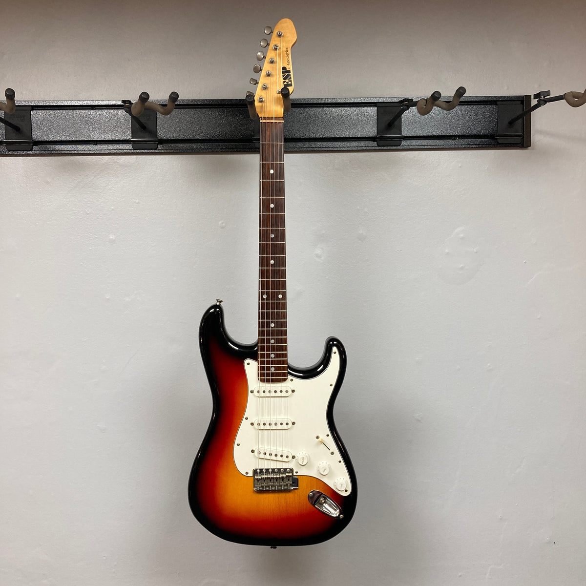 ESP Japan 400 Series Strat-style guitar displayed on a wall, showcasing its detailed craftsmanship, with a case included.