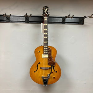 Godin 5th Avenue Jumbo P-Rail Harvest Gold electric guitar with archtop design, displayed on a wall, showcasing neck, body, and bridge details.