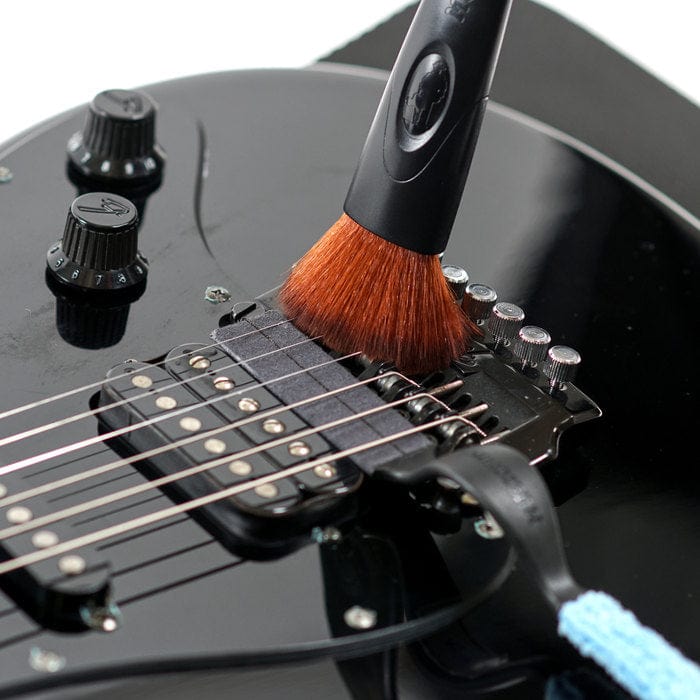 Music Nomad Total Guitar Spa Kit in use, with a brush cleaning a guitar&#39;s surface.