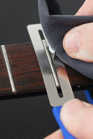 Person using a fretboard protector highlighting precision tools included in the Music Nomad Total Guitar Spa Kit for detailed guitar maintenance.