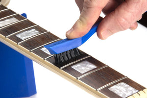 Person using brush to clean a guitar with the Music Nomad Total Guitar Spa Kit.