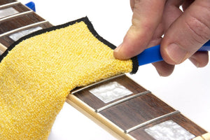 Person cleaning a guitar using the Music Nomad Total Guitar Spa Kit for comprehensive maintenance and care.