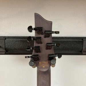 Close-up of the Schecter Omen Elite-7 Multiscale guitar headstock, showcasing tuning pegs and part of the fretboard.