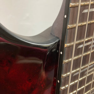 Close-up of the Schecter Omen Elite-7 Multiscale Black Cherry Burst guitar, showcasing its strings and intricate burl top.