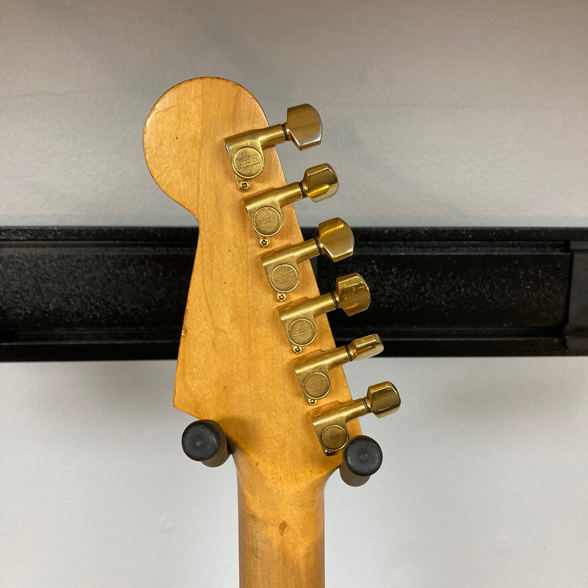 Schecter USA Super Strat 1983-1987 guitar neck close-up, featuring black and gold metal detailing.