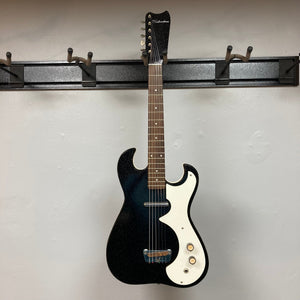 Sears Silvertone 1448 vintage black sparkle electric guitar with bolt-on neck, hanging on a wall hook, showcasing its unique design and craftsmanship.