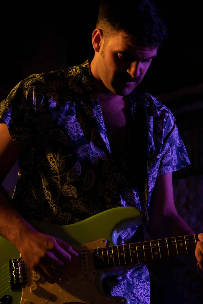 Man playing a green electric guitar.