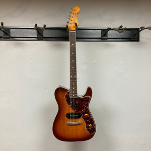 TopHat Telavarius Junior Relic Sunburst electric guitar with double bound mahogany body, rosewood fingerboard, and single dogear P90 pickup, hanging on a wall.