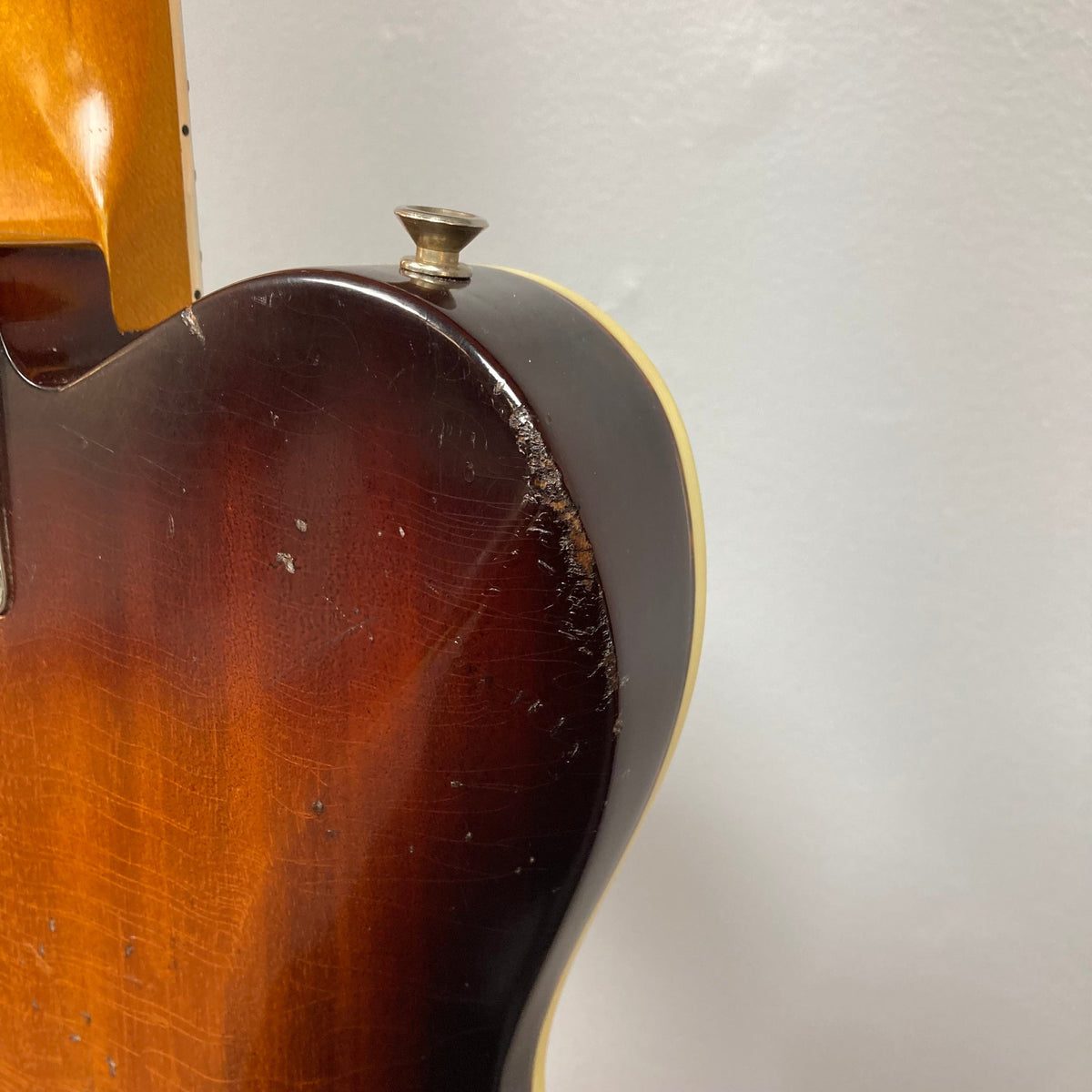 TopHat Telavarius Junior Relic Sunburst guitar, close-up showing the mahogany body with cream and tortoiseshell binding, featuring a single dogear P90 pickup and wraparound bridge.