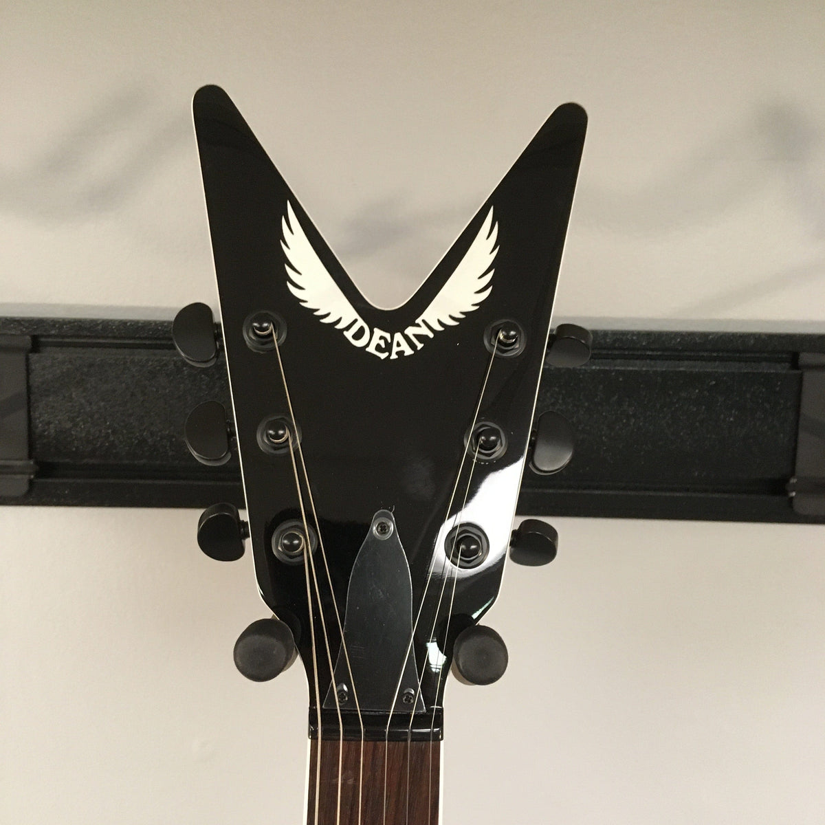 Dean Cadillac X Quilt Maple Trans Purple Burst guitar headstock close-up, showcasing white logo text and detailed string arrangement.