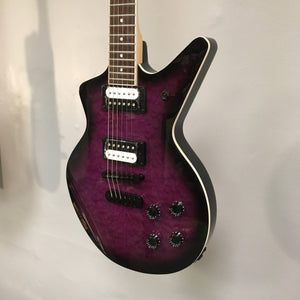 Dean Cadillac X Quilt Maple Trans Purple Burst electric guitar with 22 frets, maple neck, rosewood fingerboard, and zebra pickups, displayed on a wall.