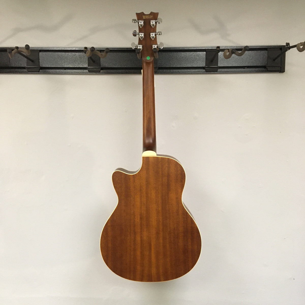 Dean CE Acoustic-Electric Resonator Guitar mounted on a wall, showcasing its modern design, eastern mahogany body, and 21 fret purple heart fingerboard.