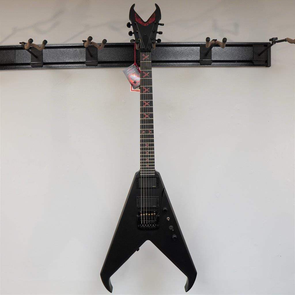 Dean Kerry King V Signature electric guitar displayed on a wall, featuring red X marks and intricate design details.