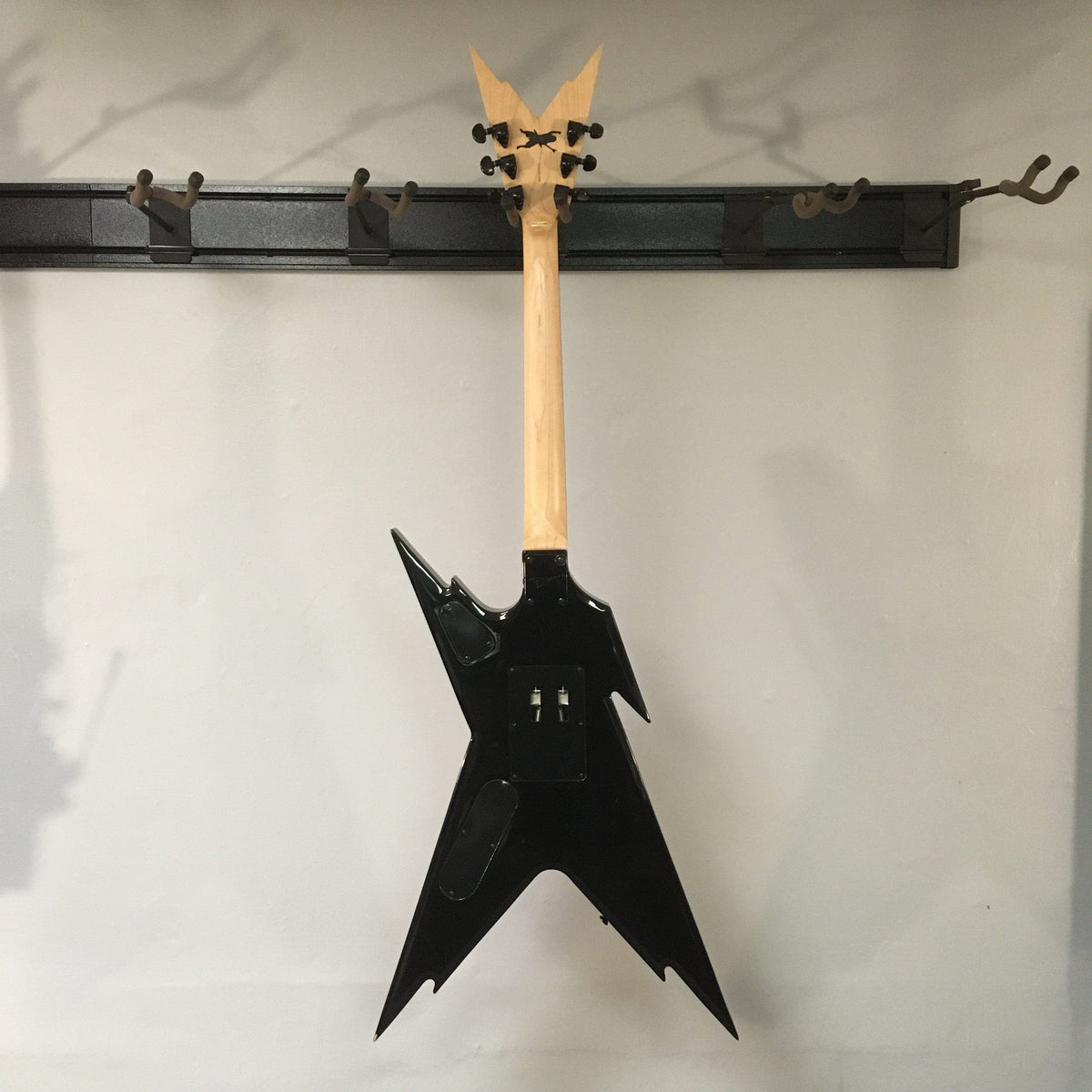 Dean Guitars Razorback Dimebag Floyd DNA Spatter electric guitar on a wall hook, showcasing its unique shape and design.