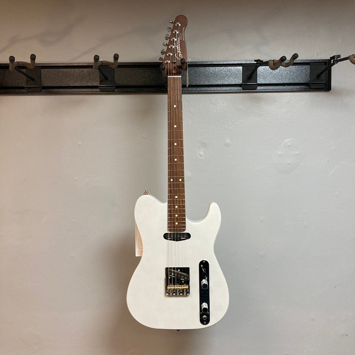 Godin Stadium HT Trans White RN electric guitar with maple neck, basswood body, and custom pickups, displayed on a wall. Comes with a gigbag.