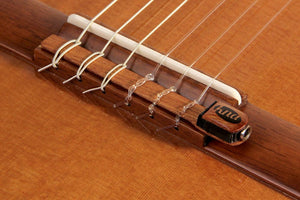 Close-up of KNA NG-1 Piezo Pick-up on a guitar, showcasing its secure installation on the tie bar beneath the strings.