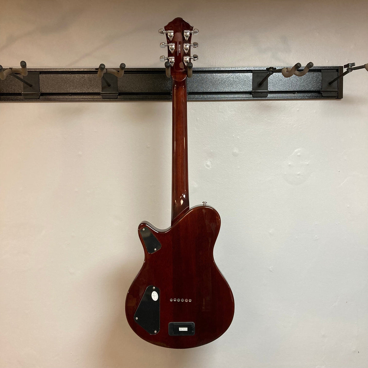 Michael Kelly Hybrid Special Ziricote Electric Acoustic Guitar mounted on a wall, showcasing its elegant ziricote top and detailed craftsmanship.