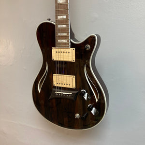 Michael Kelly Hybrid Special Ziricote electric acoustic guitar mounted on a wall, showcasing its versatile design and high-quality craftsmanship.