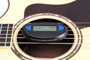 MusicNomad Hone Guitar Hygrometer clipped onto a guitar, displaying humidity and temperature for optimal instrument care.