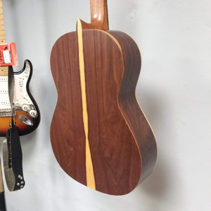 Ortega Nylon String Guitar R189SN-25TH with gig bag, featuring a solid American cedar top and Granadillo back, displayed on a wall.