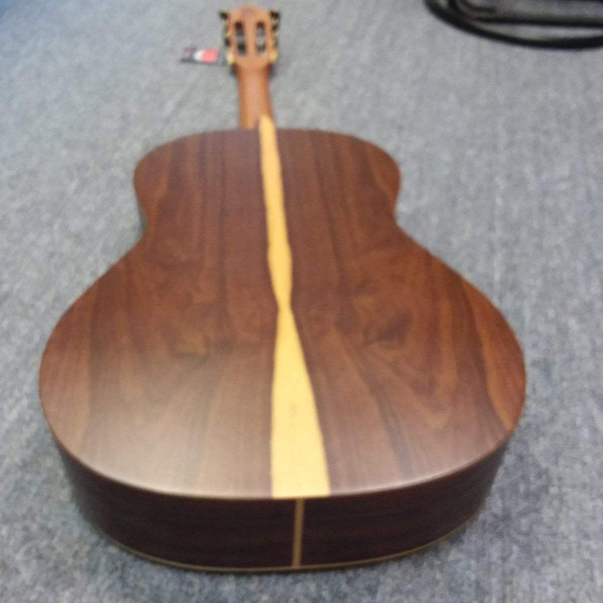 Close-up of the Ortega Nylon String Guitar R189SN-25TH with intricate wood grain and strings, highlighting its craftsmanship. Includes a gig bag.