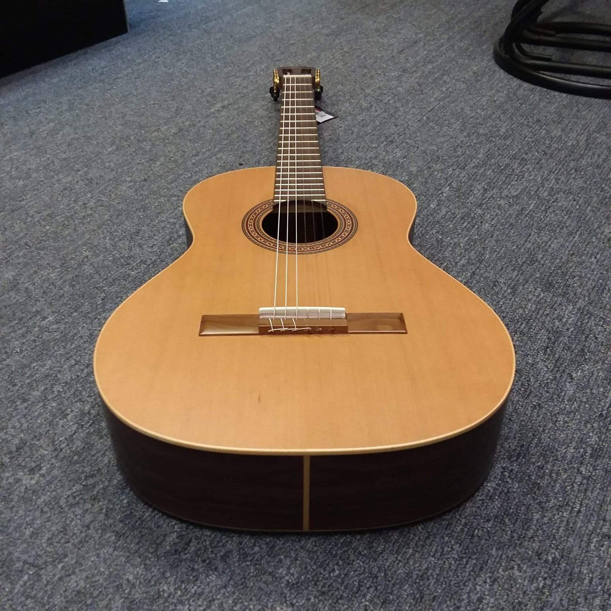 Ortega Nylon String Guitar R189SN-25TH w/bag Open Box lying on the floor, showcasing its strings and craftsmanship.